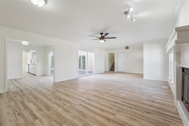 unfurnished living room with crown molding, stairway, a fireplace, and light wood-style floors