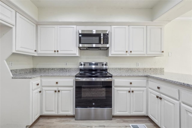 kitchen featuring white cabinetry, light stone counters, light wood-style floors, and appliances with stainless steel finishes