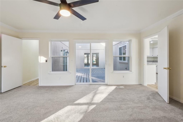 carpeted empty room featuring a ceiling fan, baseboards, and ornamental molding