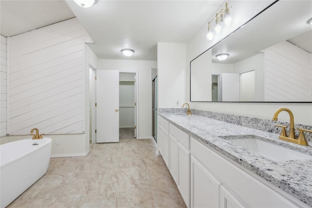 full bathroom featuring a sink, baseboards, a soaking tub, and double vanity