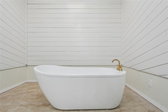 bathroom featuring wood walls and a freestanding bath