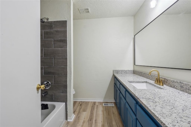 full bathroom with visible vents, a textured ceiling, vanity, and wood finished floors