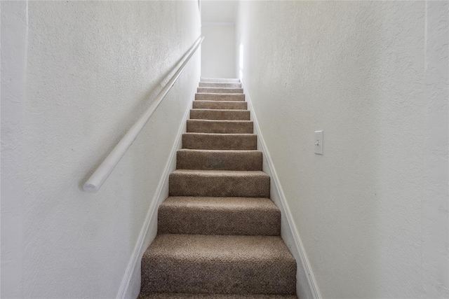 stairway with carpet flooring and a textured wall