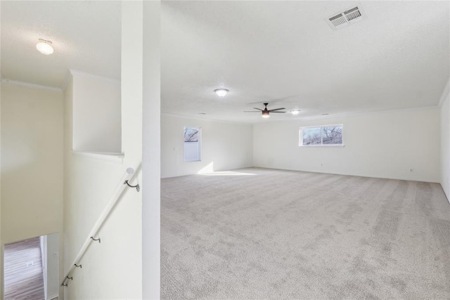 interior space with visible vents, carpet floors, a ceiling fan, and crown molding