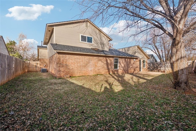 rear view of property with a yard, cooling unit, brick siding, and a fenced backyard