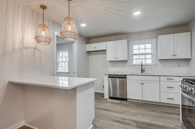 kitchen with light wood finished floors, white cabinetry, stainless steel appliances, and a sink