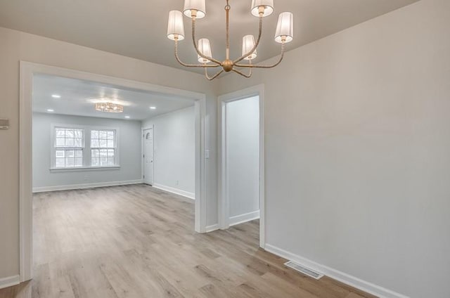 unfurnished dining area with baseboards, an inviting chandelier, visible vents, and light wood-style floors