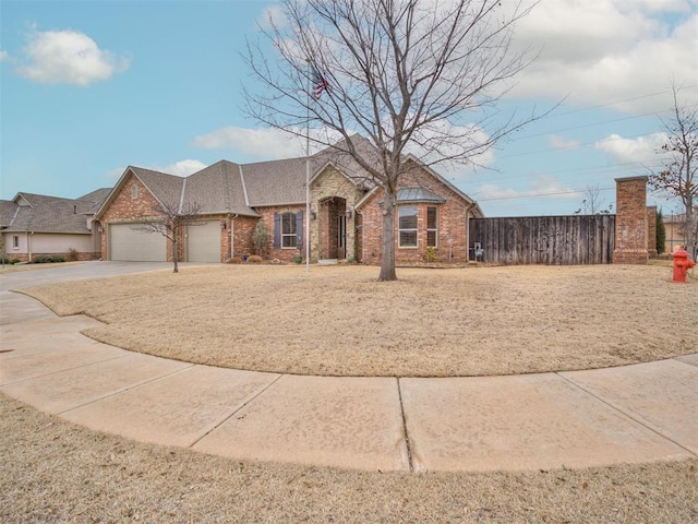 view of front of property with an attached garage, fence, concrete driveway, and brick siding