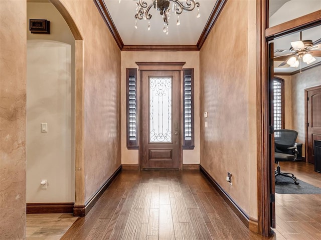 entryway with baseboards, ornamental molding, arched walkways, and wood finished floors