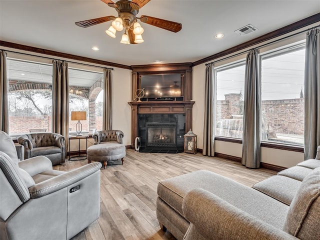 living room with a wealth of natural light, visible vents, and crown molding