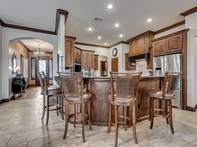 kitchen with arched walkways, appliances with stainless steel finishes, visible vents, and decorative backsplash