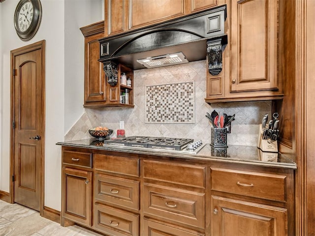 kitchen with stainless steel gas cooktop, custom exhaust hood, tasteful backsplash, dark countertops, and brown cabinetry