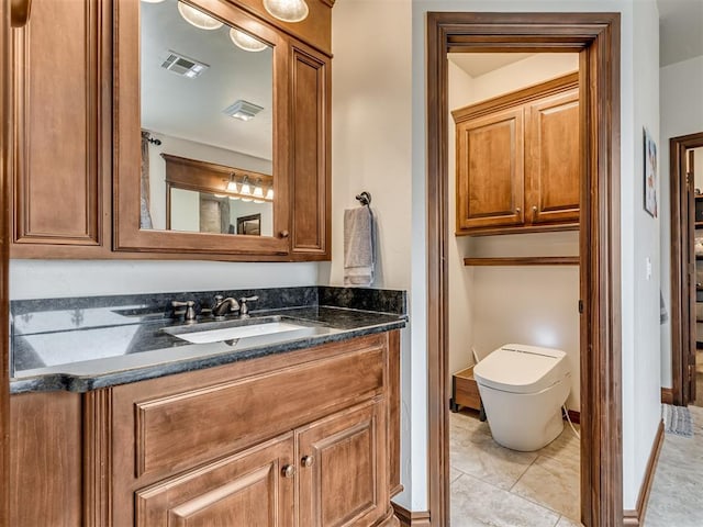 bathroom featuring toilet, vanity, visible vents, baseboards, and tile patterned floors