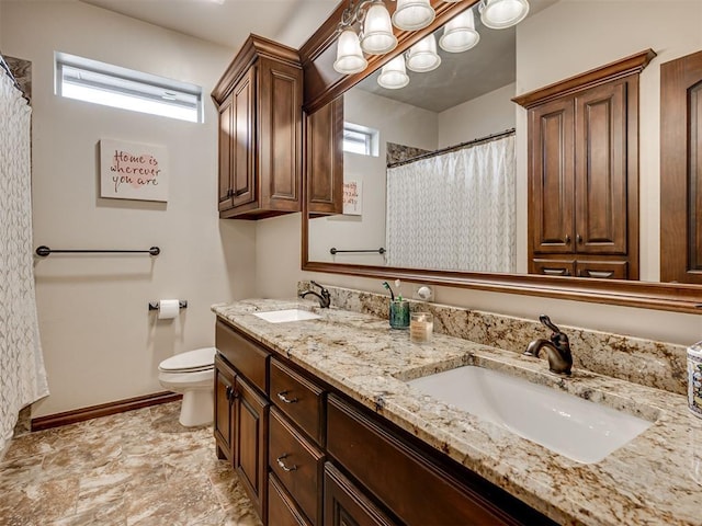 bathroom with toilet, a sink, and a wealth of natural light