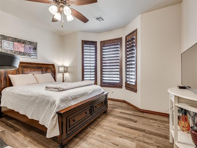 bedroom featuring light wood finished floors, a ceiling fan, visible vents, and baseboards