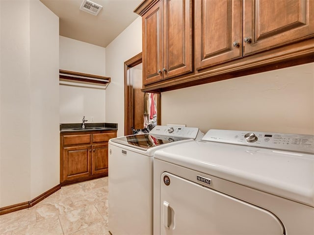 laundry room featuring cabinet space, baseboards, visible vents, washing machine and clothes dryer, and a sink