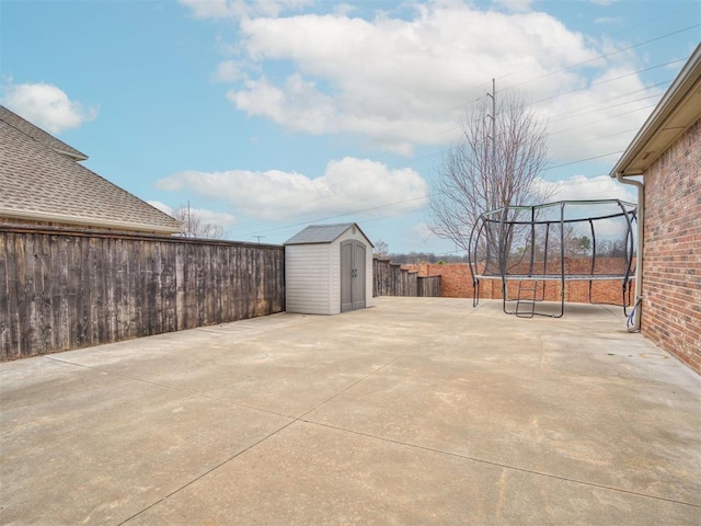 view of patio / terrace with a shed, a trampoline, a fenced backyard, and an outbuilding