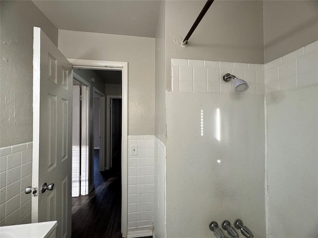 full bathroom with a wainscoted wall, tile walls, and walk in shower