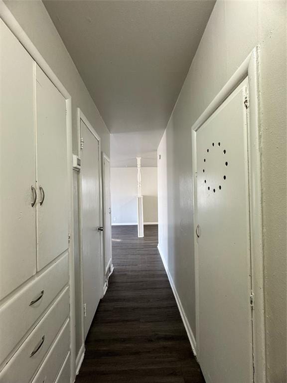 hallway featuring dark wood-type flooring and baseboards