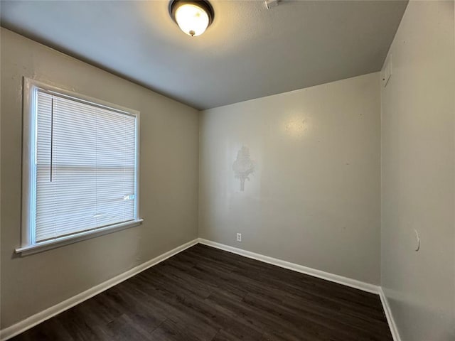 spare room with baseboards and dark wood finished floors