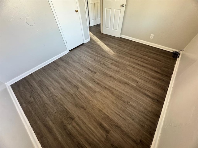 unfurnished bedroom featuring baseboards and dark wood-type flooring