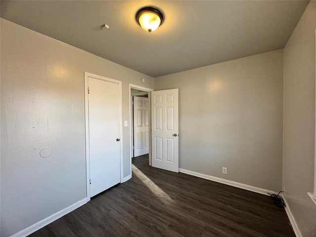 unfurnished bedroom featuring dark wood-style floors and baseboards