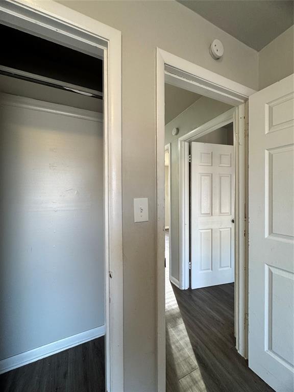 hallway with dark wood-style floors and baseboards