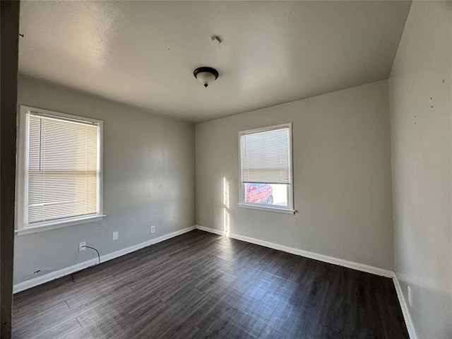 unfurnished room featuring dark wood-type flooring and baseboards