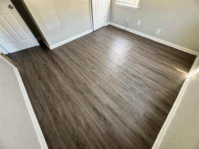 unfurnished bedroom featuring dark wood-style floors, baseboards, and a closet