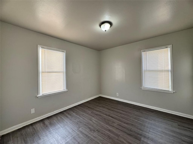 unfurnished room featuring dark wood-style floors, baseboards, and a wealth of natural light