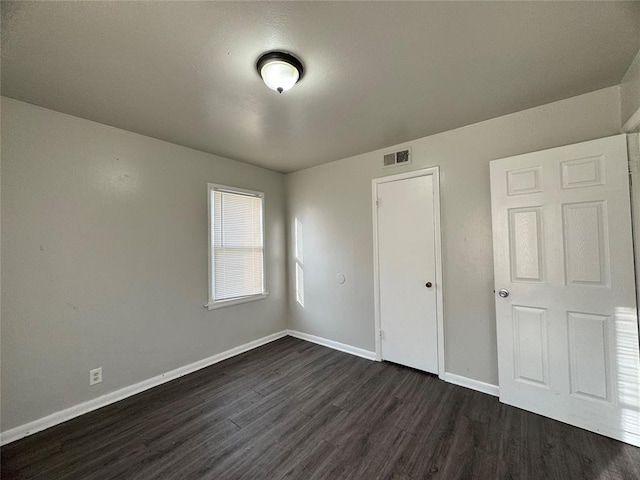 unfurnished bedroom with dark wood finished floors, visible vents, and baseboards