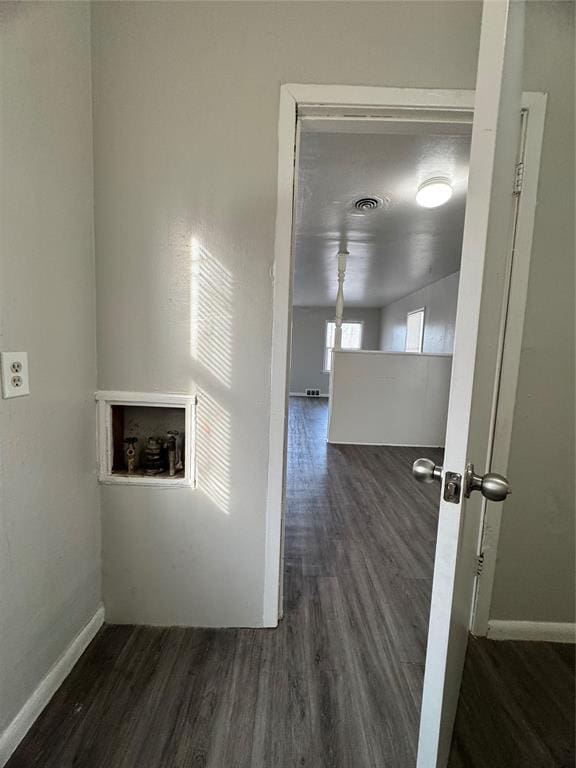 hall featuring visible vents, baseboards, and wood finished floors