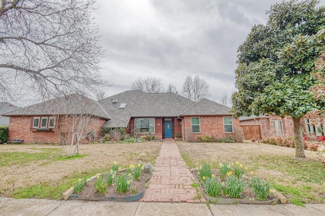 view of front of property featuring a front lawn, brick siding, and a shingled roof