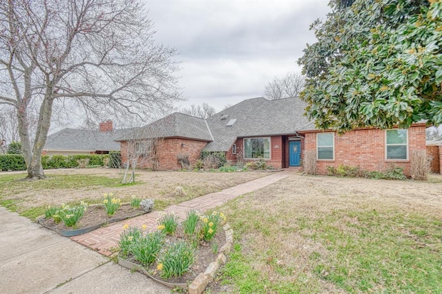 view of front of home featuring a front yard, brick siding, and a shingled roof