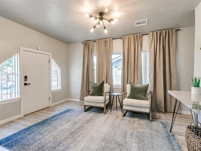 sitting room with wood finished floors, visible vents, and baseboards