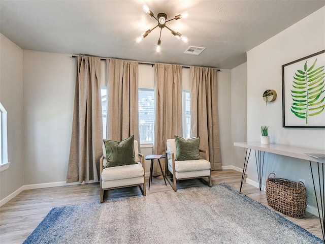 living area with baseboards, visible vents, and wood finished floors