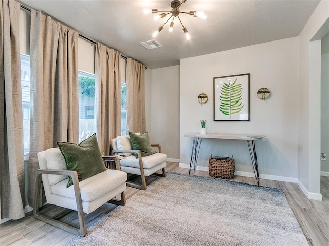 living area with a chandelier, visible vents, light wood-style flooring, and baseboards