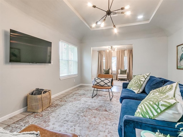 living area featuring baseboards, wood finished floors, a raised ceiling, and a notable chandelier