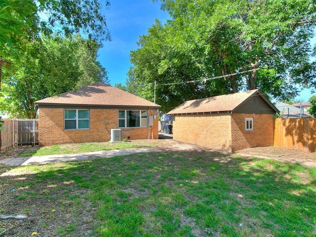 rear view of house featuring brick siding, a lawn, and a fenced backyard