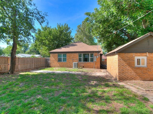 rear view of house with central AC unit, a lawn, a fenced backyard, crawl space, and brick siding