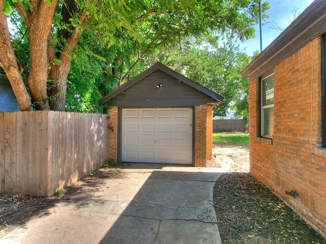 detached garage with concrete driveway and fence