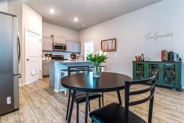 kitchen with wood tiled floor, stainless steel appliances, light countertops, gray cabinetry, and recessed lighting