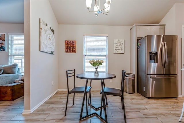 dining area with wood tiled floor, a notable chandelier, lofted ceiling, and baseboards