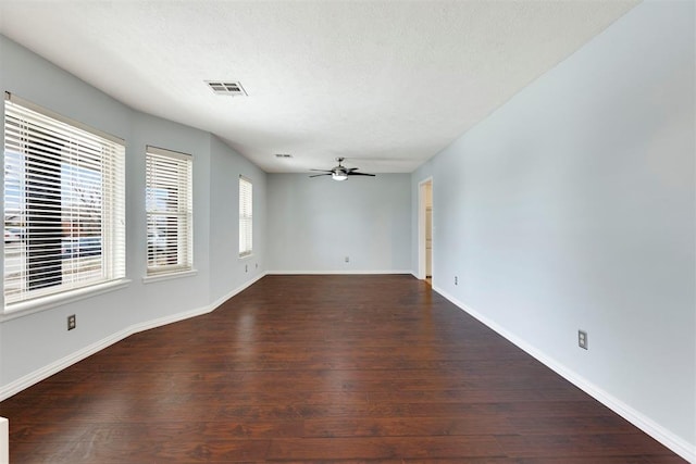 empty room with a ceiling fan, visible vents, baseboards, and wood finished floors