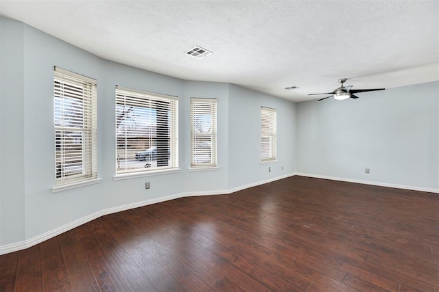 spare room with a textured ceiling, wood-type flooring, visible vents, and baseboards