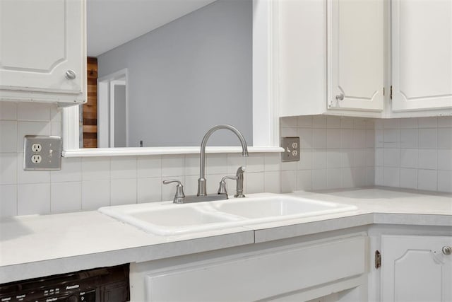 kitchen featuring dishwashing machine, a sink, white cabinetry, light countertops, and tasteful backsplash