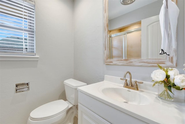 bathroom with a stall shower, a textured wall, vanity, and toilet