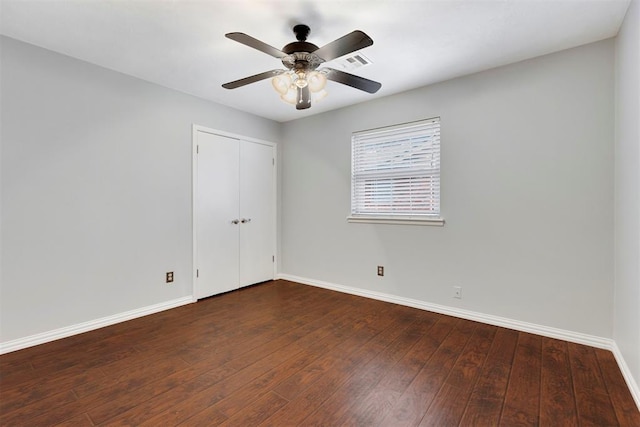 empty room featuring a ceiling fan, visible vents, baseboards, and hardwood / wood-style flooring