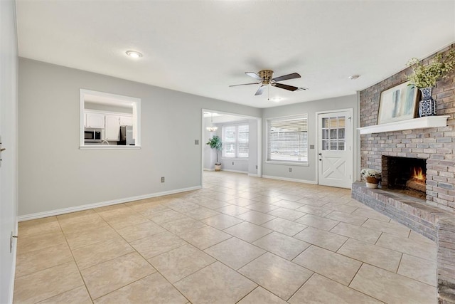 unfurnished living room featuring light tile patterned floors, ceiling fan, a fireplace, and baseboards