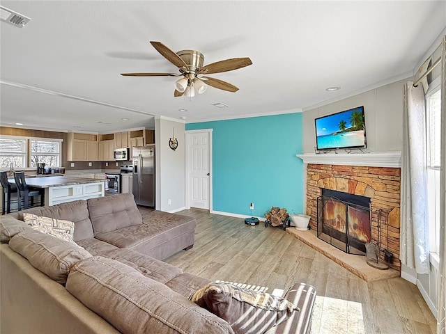 living area with light wood-style floors, visible vents, a fireplace, and crown molding